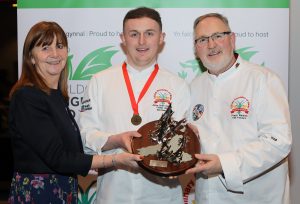 Junior Chef of Wales winner Sam Everton receives the dragon trophy from Minister for Rural Affairs Lesley Griffiths and CAW president Arwyn Watkins, OBE.